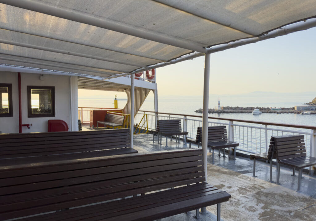 Sunny summer morning, the empty car and passenger ferry leaves the port of Bozcaada. No people. A Turkish island in the North Aegean Sea